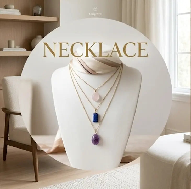 Three layered gold chain necklaces on jewelry bust displaying rose quartz, lapis lazuli, and amethyst crystal pendants in a warm minimalist interior
