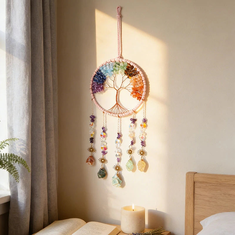 Handmade 7 chakra crystal dream catcher wall hanging in boho bedroom with warm natural light, candles and book on nightstand