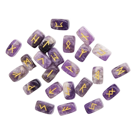 Complete 25-piece natural amethyst Elder Futhark rune stone set with gold-engraved Viking symbols scattered on white background, purple crystal divination stones