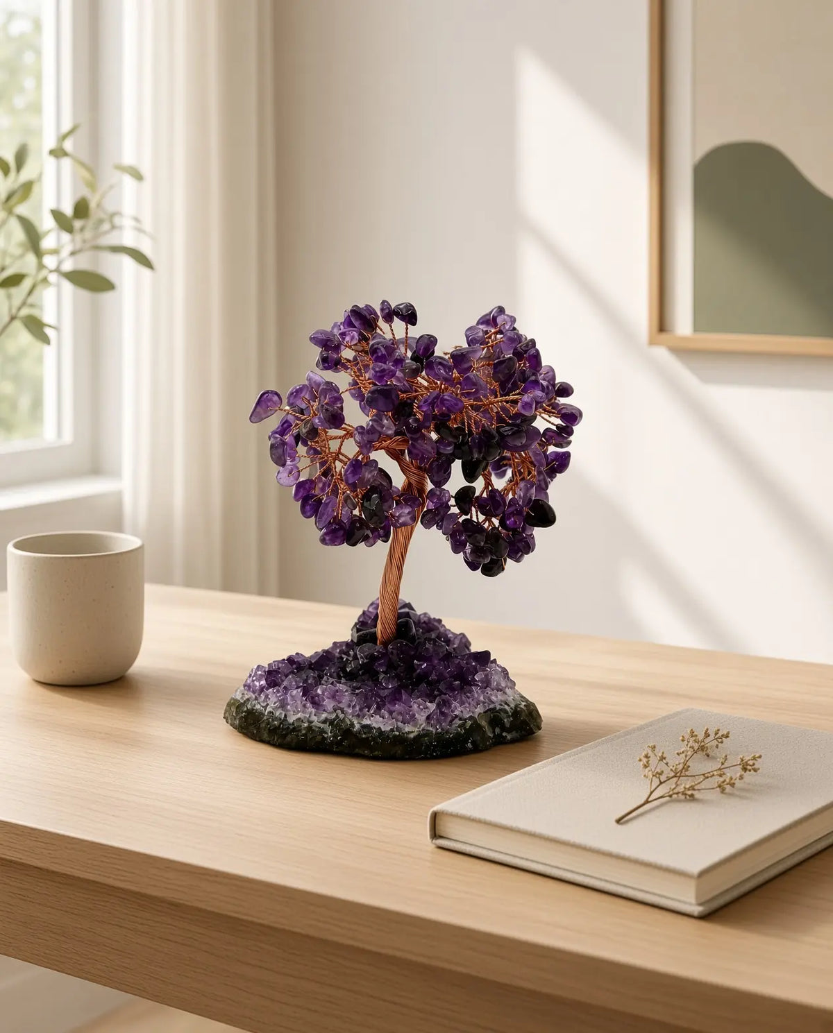 Amethyst crystal tree on a sunlit wooden desk with mug and notebook
