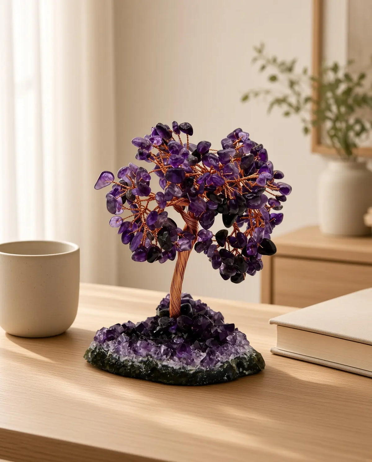 Amethyst crystal tree on a wooden table with mug and book