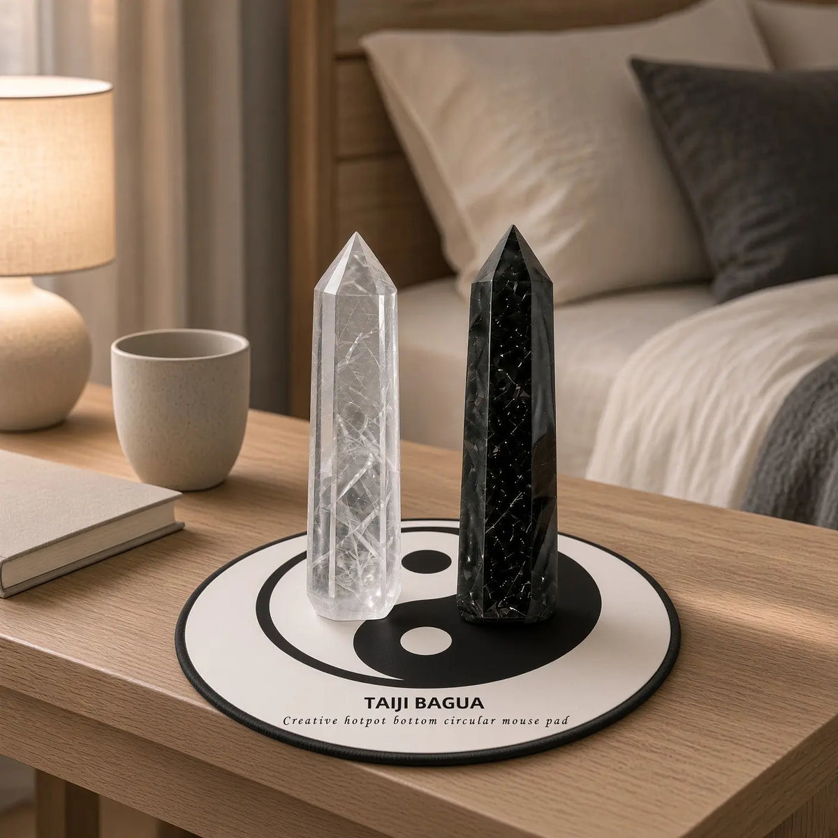 Clear quartz and black obsidian towers standing on a yin-yang mat on a bedroom nightstand