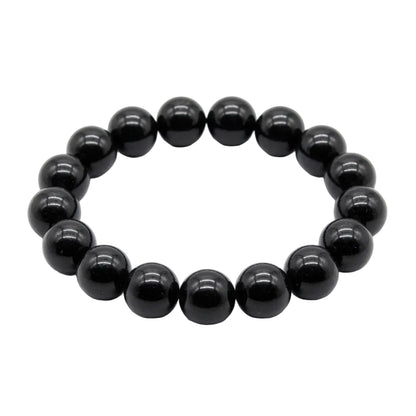 Natural black tourmaline polished bead bracelet with deep glossy 12mm round stones laid flat on white background, protection and grounding crystal jewelry