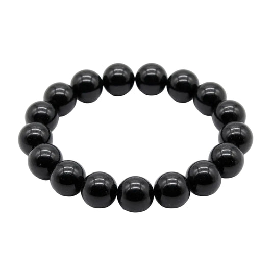 Natural black tourmaline polished bead bracelet with deep glossy 12mm round stones laid flat on white background, protection and grounding crystal jewelry