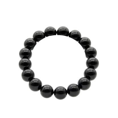 Natural black tourmaline polished bead bracelet with deep glossy 12mm round stones laid flat on white background, protection and grounding crystal jewelry