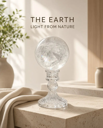 Clear quartz sphere on a glass stand with “The Earth” brand text