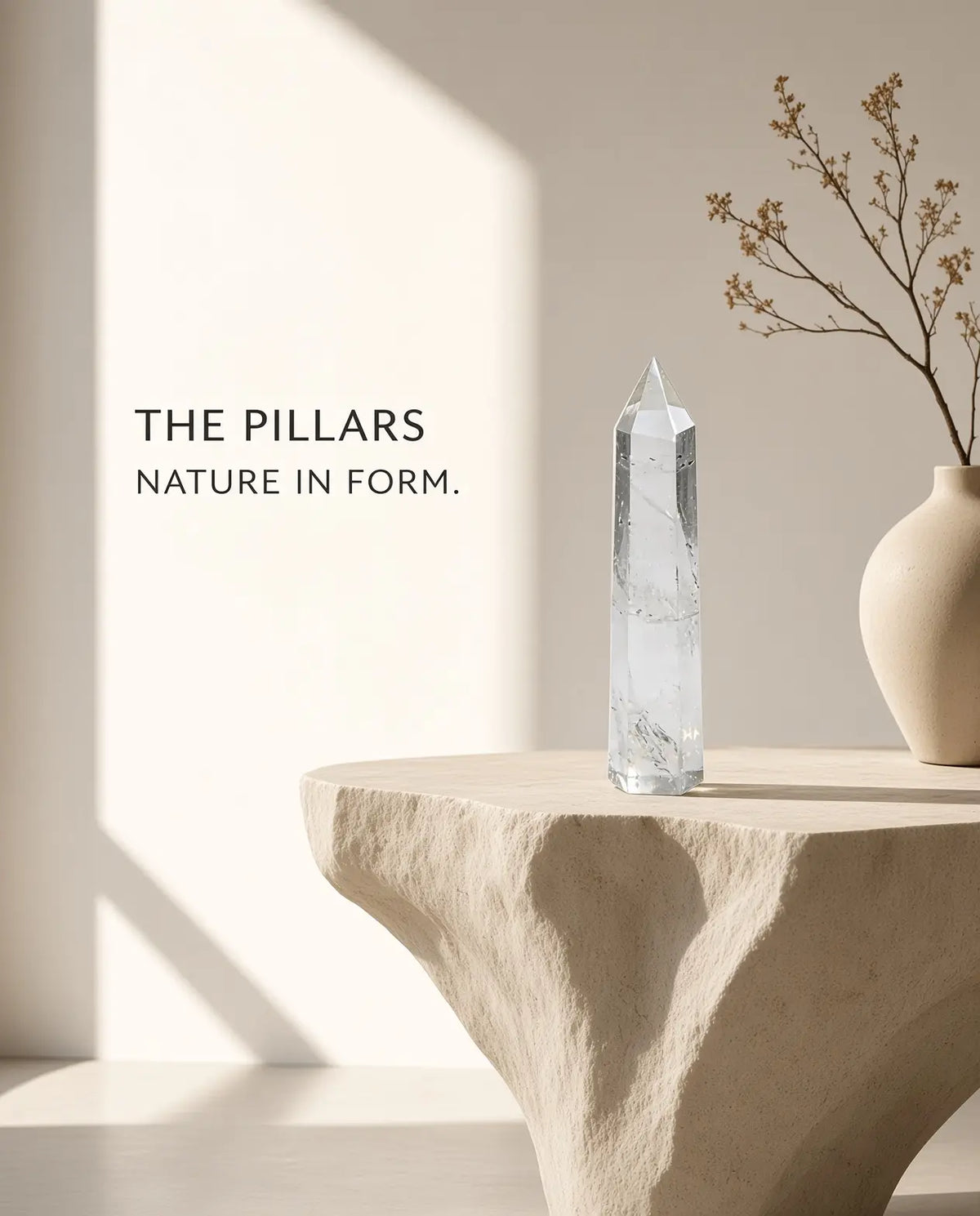 Clear quartz crystal tower on a stone table with “The Pillars” brand text