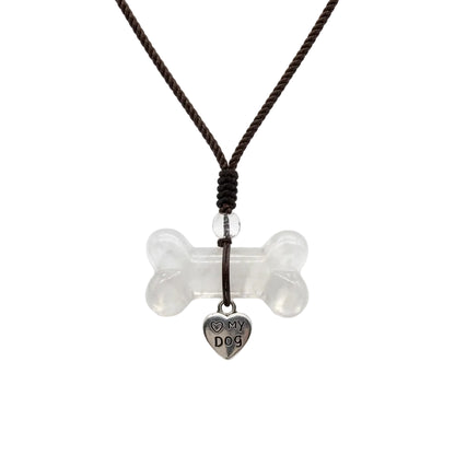 Natural clear quartz dog bone carved crystal pendant necklace with silver Love My Dog heart charm on adjustable brown braided cord, healing crystal jewelry for dog moms on white background