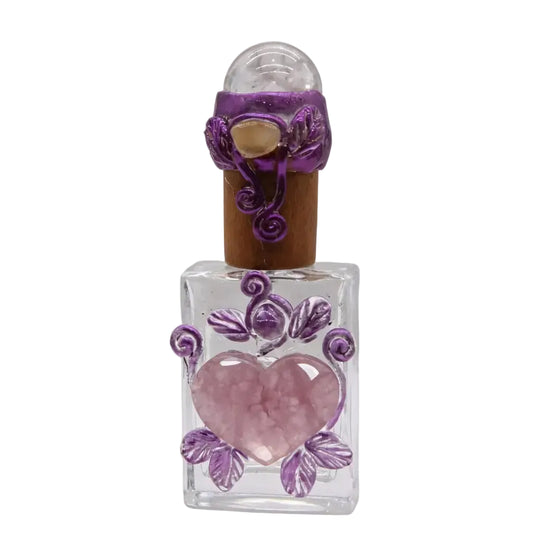 Handcrafted clear glass perfume bottle with rose quartz heart center, purple wire-wrapped leaf decoration, clear quartz sphere stopper and natural cork, healing ritual vessel on white background