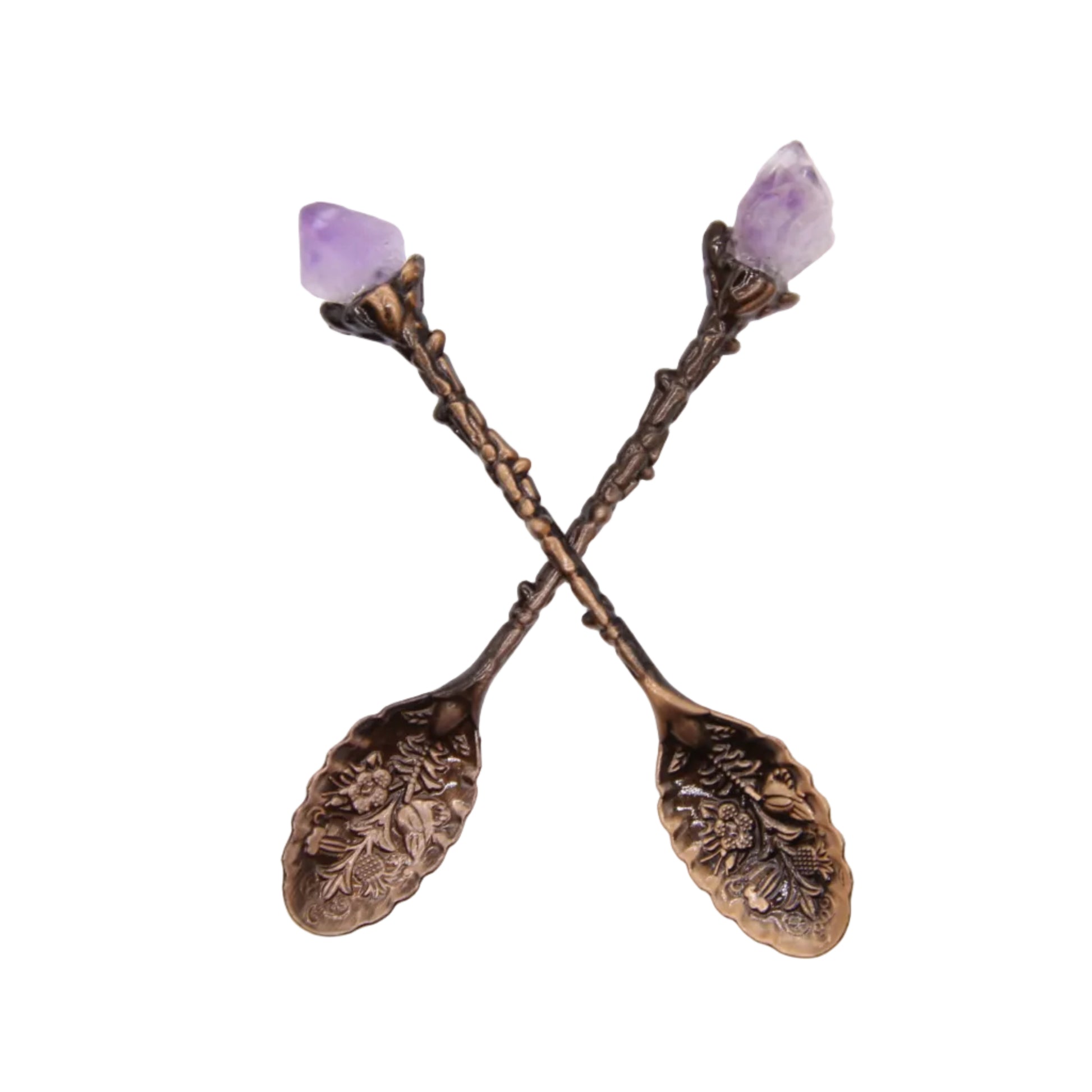 Two handcrafted antique brass botanical engraved stirring spoons with natural raw amethyst crystal points, crossed display on white background, ritual tea and altar tools