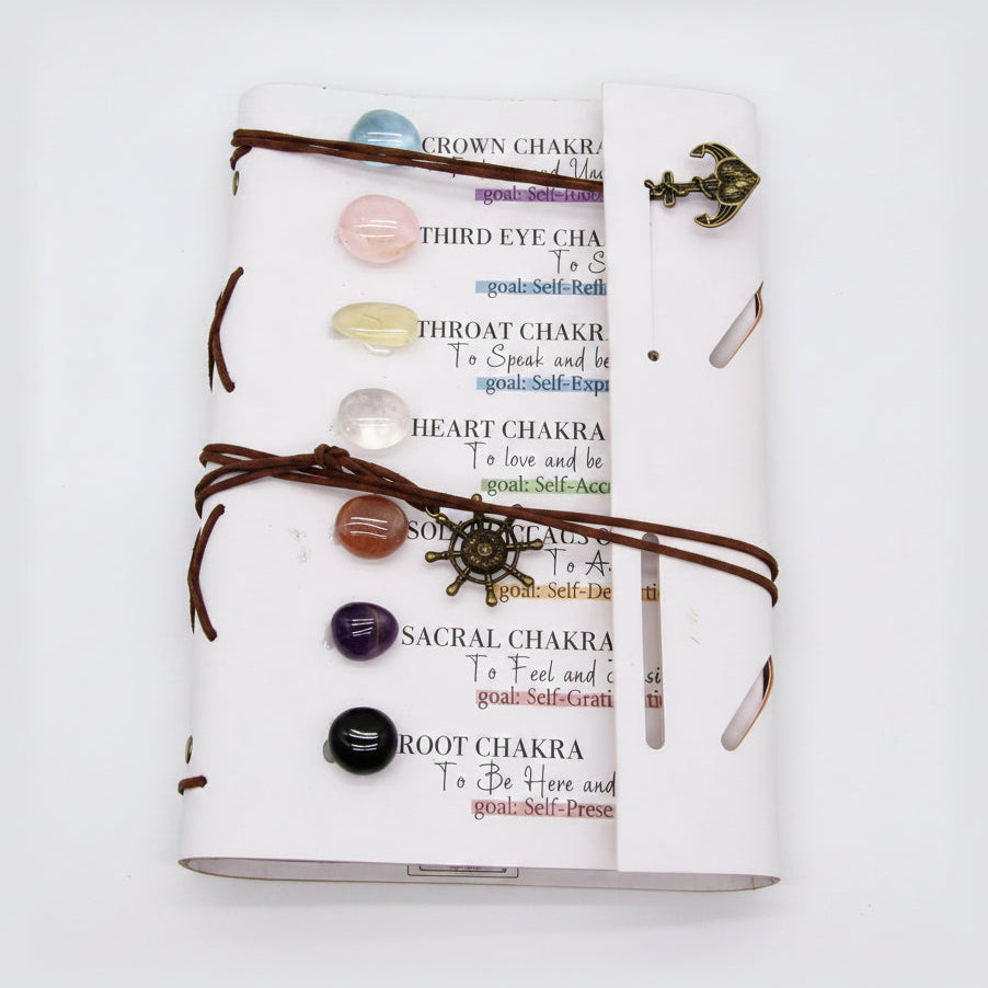 7 chakra crystal journal with tumbled gemstones, leather wrap, and chakra affirmations on a white background