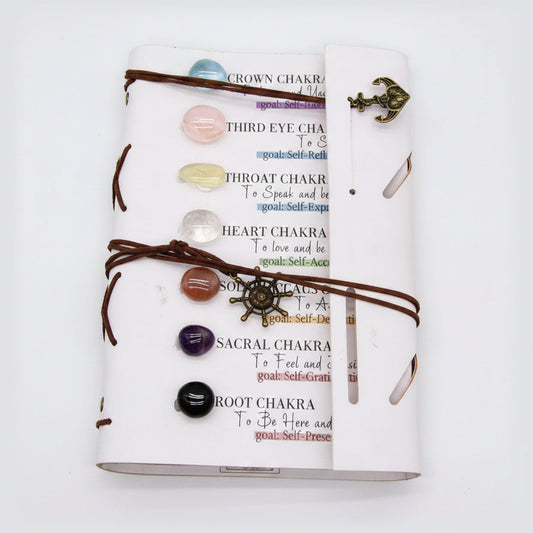 7 chakra crystal journal with tumbled gemstones, leather wrap, and chakra affirmations on a white background