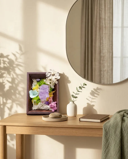 Amethyst framed landscape on an oak console under a round mirror, with a small vase and book