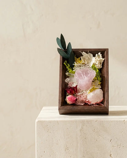 Rose quartz framed landscape with dried roses and eucalyptus in a dark wood box