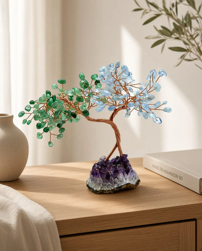 Rose quartz and aquamarine crystal tree on a wooden table with cup and book