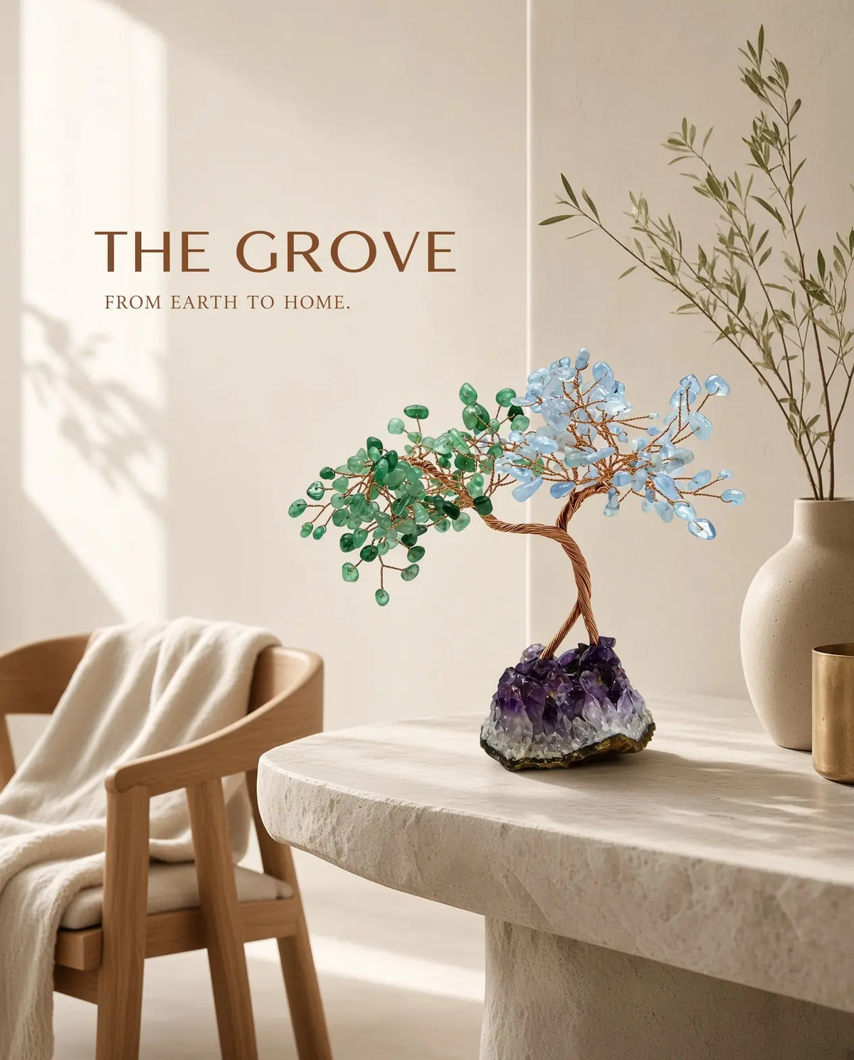 Rose quartz and aquamarine crystal tree on a stone ledge with “The Grove” brand text