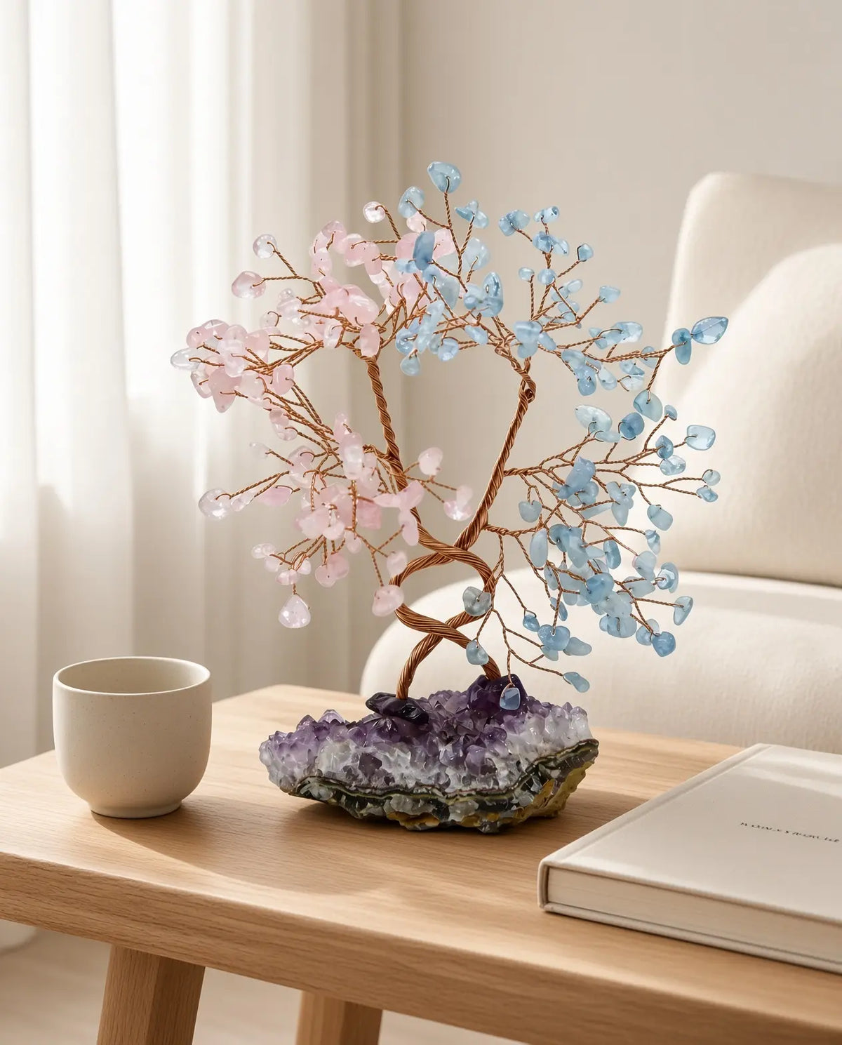 Rose quartz and aquamarine crystal tree on a wooden table with cup and book