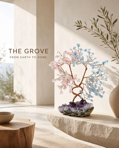 Rose quartz and aquamarine crystal tree on a stone ledge with “The Grove” brand text