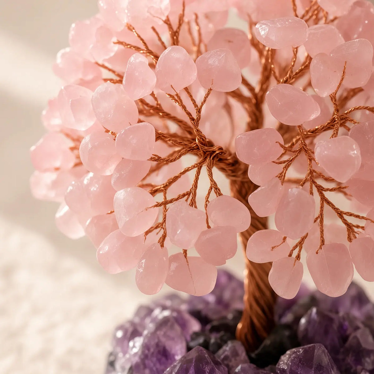 Detail of rose quartz chips and copper wire branches on an amethyst crystal tree