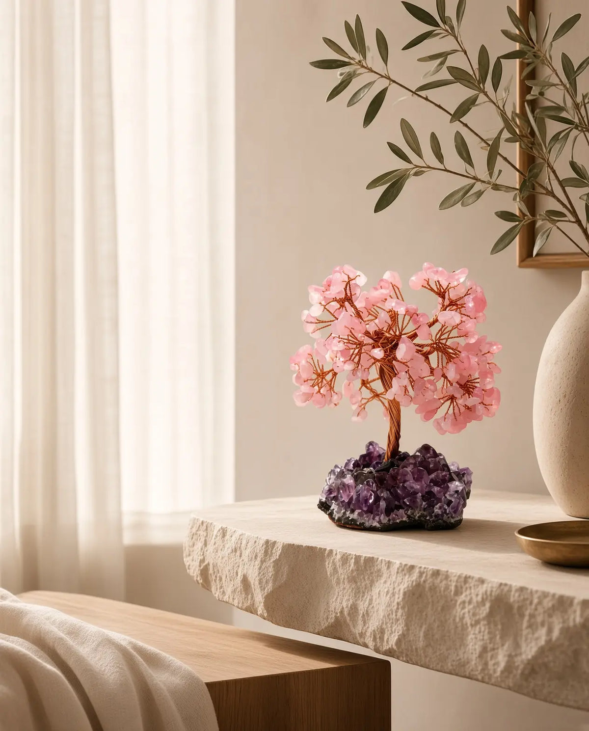 Rose quartz crystal tree on amethyst base styled on a stone console in a sunlit room