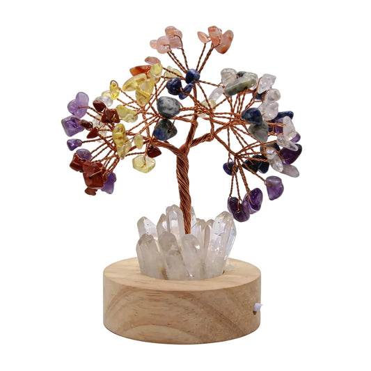 7 Chakra Crystal Tree of Life LED Lamp with glowing clear quartz base, warm light on wooden nightstand in a cozy bedroom.