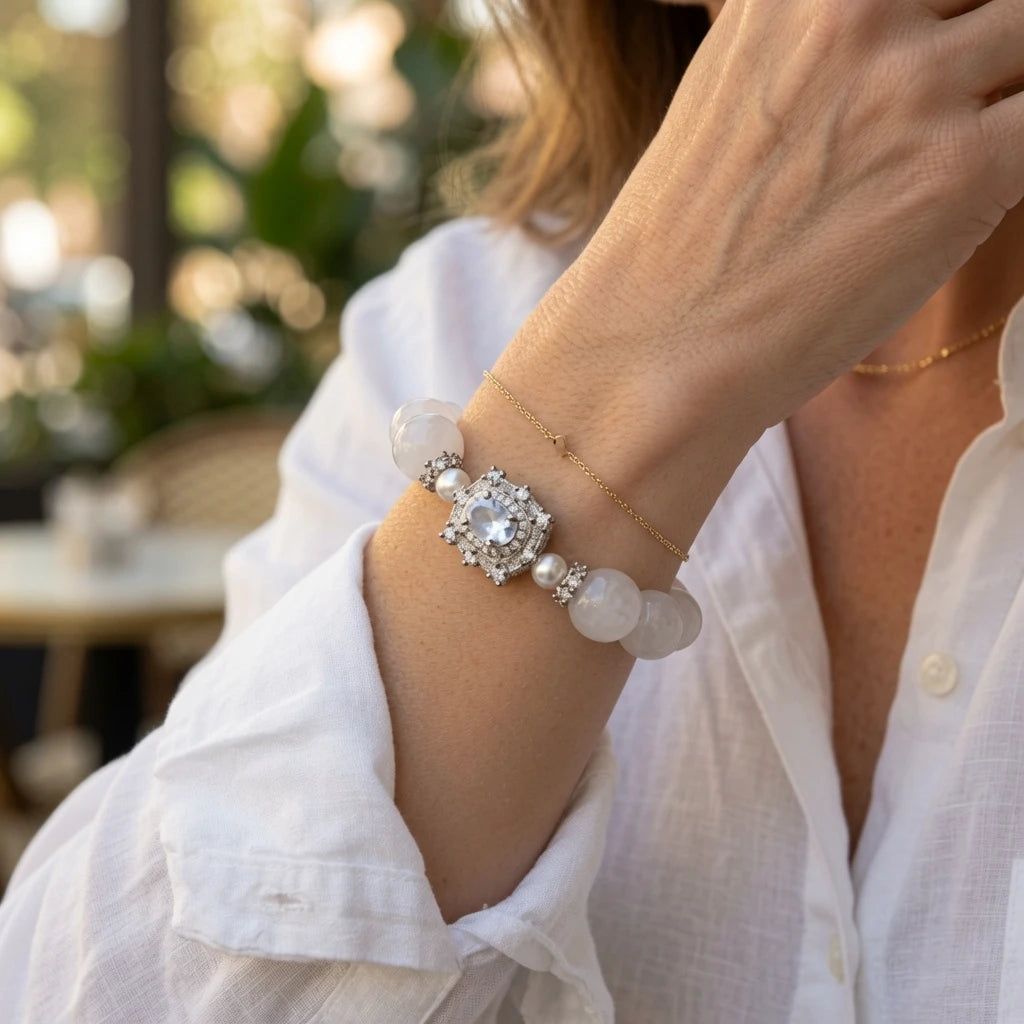 Close-up of ornate silver pave CZ centerpiece with blue-violet focal stone on white jade bead bracelet, luxury crystal healing bracelet detail with natural stone milky translucency