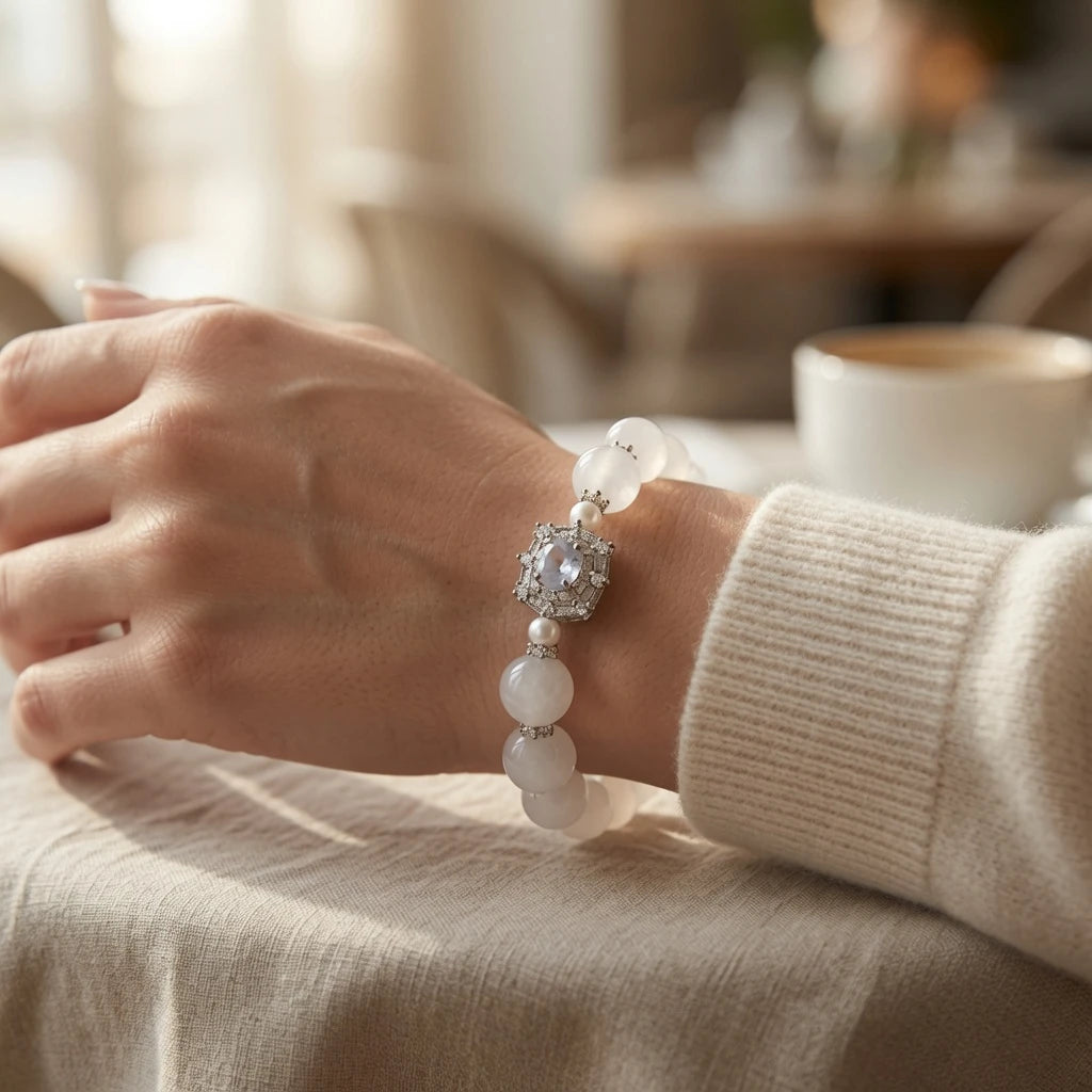 White jade crystal bracelet stacked with clear quartz and moonstone bracelets on wrist showing crown chakra crystal healing layering style for feminine elegant jewelry